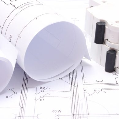 Rolled electrical diagrams and electric fuse lying on construction drawing of house, drawings for the projects engineer jobs